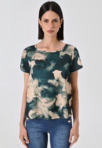 Top a maniche corte con stampa floreale in teal e beige, realizzato in tessuto morbido, con scollatura rotonda e vestibilità ampia.