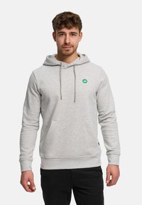 Grå huvtröja med en kenguruficka, dragsko i luvan och en liten grön logotyp på bröstet. Har ribbade muddar och fåll.