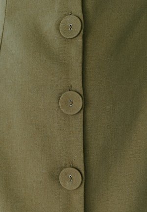 Tela verde oliva con un acabado texturizado, que presenta cuatro botones redondos y costuras visibles a lo largo del placket de botones.