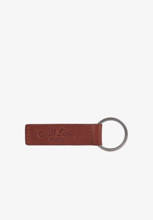 Brauner Leder-Schlüsselanhänger mit Metallring und eingeprägtem Text "Gusti Leder studio" am Lederband.