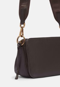 Borsa a tracolla in pelle marrone scuro con ampia tracolla in tessuto e chiusura metallica dorata, con mostra della patta frontale e dettaglio della zip laterale.