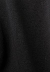 Tissu noir avec une apparence lisse et légèrement texturée. Le matériau semble léger et extensible, adapté pour des vêtements décontractés.