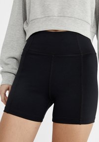 Zwarte hoge taille shorts van rekbaar materiaal, met een strak ontwerp en contrasterende naden en een zachte textuur.