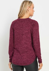 Bordeaux lange mouwen shirt met een gestructureerd, gemêleerd patroon. Kenmerkt zich door een ronde zoom en raglanmouwen, gemaakt van zachte, stretchy stof.