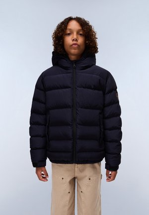 Giacca puffer blu navy con cappuccio, caratterizzata da una chiusura con zip, polsini elastici e un design trapuntato. Abbinata a pantaloni beige a gamba larga.