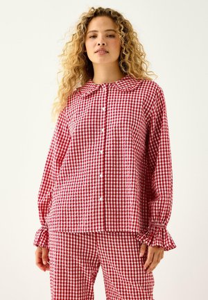 Roter und weißer Karo-musterer Schlafanzug mit einem kragenlosen Hemd mit Knöpfen und Rüschensäumen sowie passenden Hosen. Aus leichtem Baumwollmaterial.