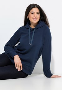 Sudadera con capucha de color azul marino en material suave, con un bolsillo tipo canguro, cordón ajustable y puños acanalados. Corte casual con mangas largas.
