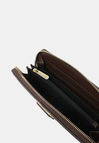 Portafoglio in pelle marrone con cerniera dorata, scomparti interni e fodera in tessuto nero. Dispone di più slot per carte e una tasca con zip.