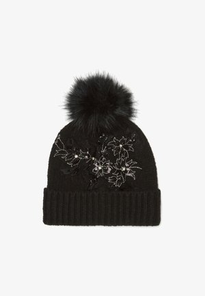 Gorro de punto negro con puño acanalado, que presenta bordados florales en plata y negro, y un gran pompón de pelo sintético negro en la parte superior.