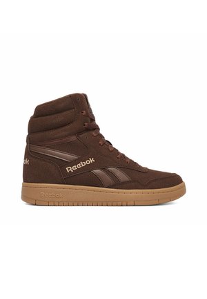 Sneaker Reebok marrone alta con tomaia in pelle scamosciata, colletto imbottito, chiusura con lacci e suola in gomma marrone su sfondo bianco.