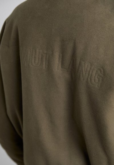 Felpa verde oliva con una finitura morbida e texturizzata. Presenta una cucitura in rilievo con la scritta "MIUT LANG" sul retro. Design semplice e informale.