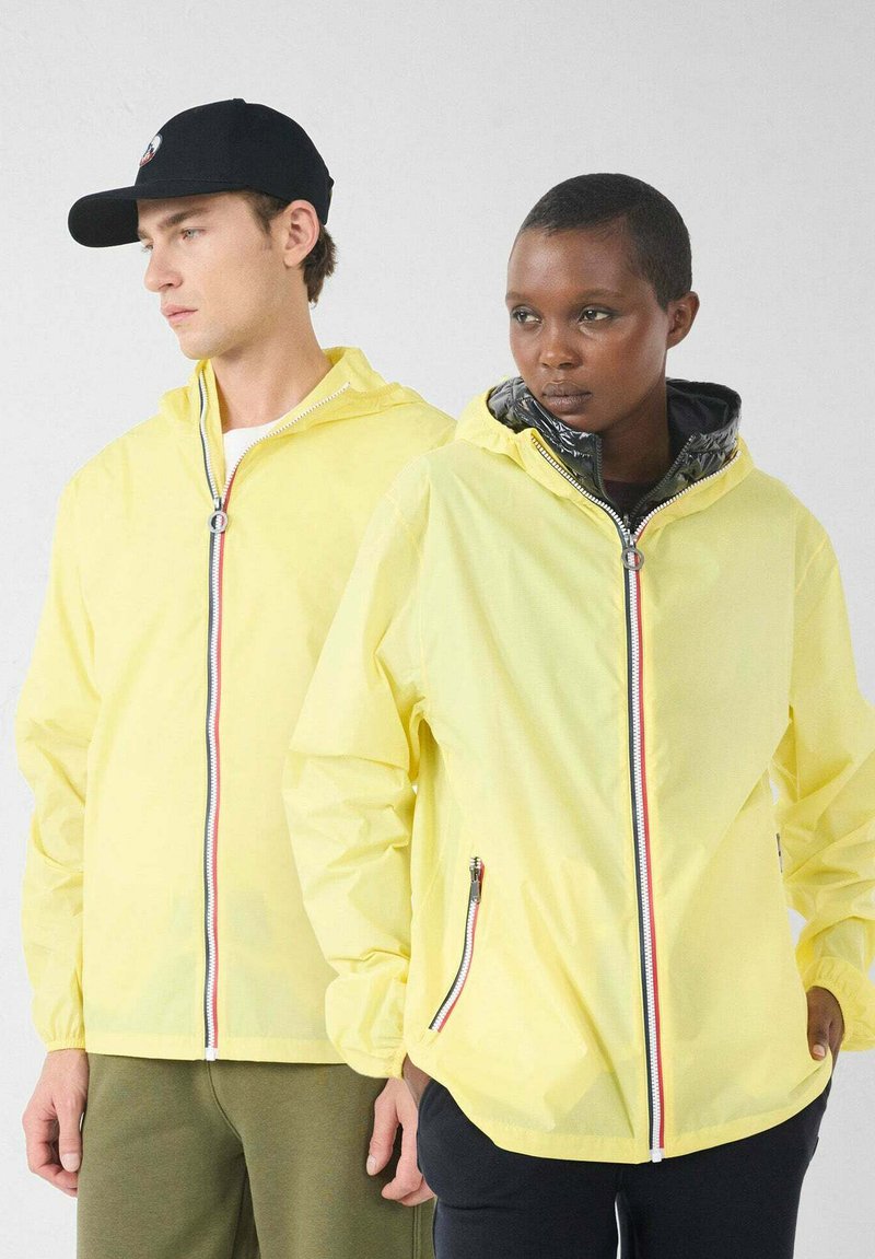 Geelgewichtige jacks met voorritsen in rood, wit en blauw en met capuchons. Eén jack heeft een glanzende, zwarte binnenvoering.