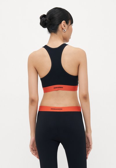 Zwarte sportbeha met racerback-ontwerp, voorzien van een rode band met de tekst "DSQUARED2". Draag het met bijpassende zwarte leggings, die een soepele textuur tonen.
