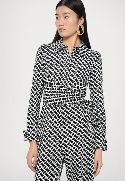 Μαύρο και άσπρο πουκάμισο-φόρεμα με μοτίβα, με γιακά, κουμπιά στο μπροστινό μέρος, μακριά μανίκια και ζώνη στη μέση. Γεωμετρικό σχέδιο αλυσίδας.