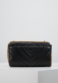 Czarna prostokątna torebka ze skóry z wzorem w jodełkę, złotym łańcuszkiem i zamkiem błyskawicznym. Teksturowana powierzchnia z gładkimi akcentami.