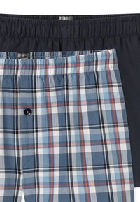 Due paia di pantaloni corti da uomo; uno in tinta unita blu navy scuro, l'altro a quadri blu con linee bianche, rosse e nere. Vita elastica, dettaglio con bottone sui pantaloni a quadri.