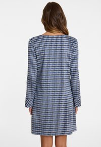 Blaue und weiße Hahnentrittmuster-Kleid mit langen Ärmeln, rundem Ausschnitt und geradem Schnitt, das eine glatte Textur aufweist.