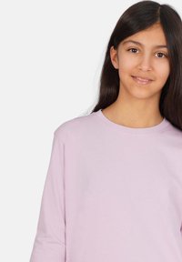 Ljuslila långärmad skjorta i mjukt material, med rund hals och avslappnad passform. Slät yta utan synliga mönster eller detaljer.