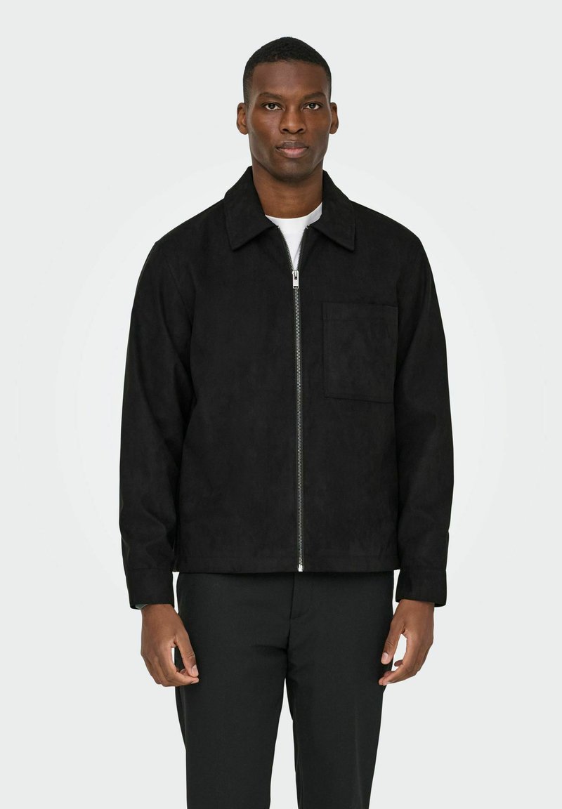 Črna suknjič iz ante z ovratnikom, sprednjim zip zapiranjem in enim žepom na prsih. Ima gladko teksturo in prilega se telesu.