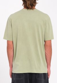 Camiseta de manga corta verde claro hecha de una tela suave, con cuello redondo, ajuste relajado y bordes limpios sin cierres visibles.