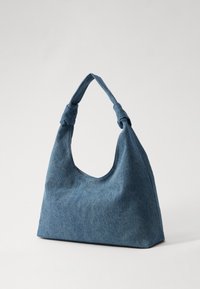 Denim skulderveske i mørkeblå med rund topp og knyttet håndtak. Stoffer har en myk tekstur, med en jevn og glatt overflate.