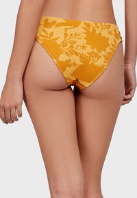 Žluté bikiny s květinovým potiskem a vysokým pasem, vyrobené z texturované látky a s bezšvovými okraji pro hladké nošení.