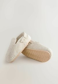 Gray felt slip-on shoes with a rounded toe, a strap across the upper, and a textured beige rubber sole. Cutout on the side for breathability.