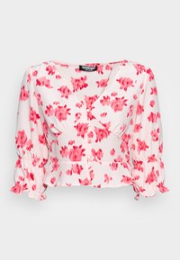 Blusa cropped feita de tecido leve, com um fundo branco e padrões florais em rosa, decote em V e mangas bufantes com punhos franzidos.