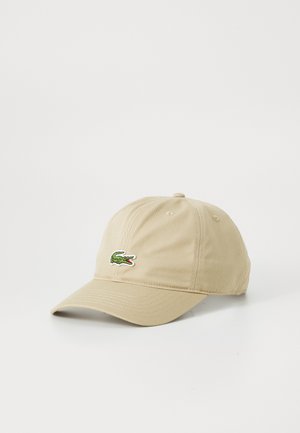 Beige bomull baseball cap med buet skjerm og brodert grønn krokodillelogo på fronten. Justerbar stropp bak.