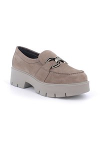 Scarpa slip-on in suede beige con una robusta suola piatta grigia e dettagli metallici decorativi sulla parte anteriore. Punta arrotondata e dettagli con cuciture.