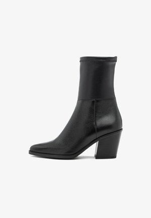 Juodas odinis kulkšninis botas su smailiu pirštu, tekstūruota apdaila, elastiniu apvadu ir storu kulnu. Yra lygus padas, užtikrinantis komfortą.