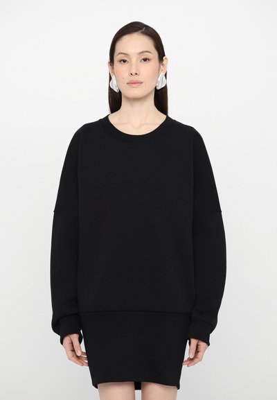 Zwart sweatshirt met lange mouwen en een ronde halslijn, voorzien van een getextureerd logo op de voorkant. Zachte, gladde stof met een ontspannen pasvorm.