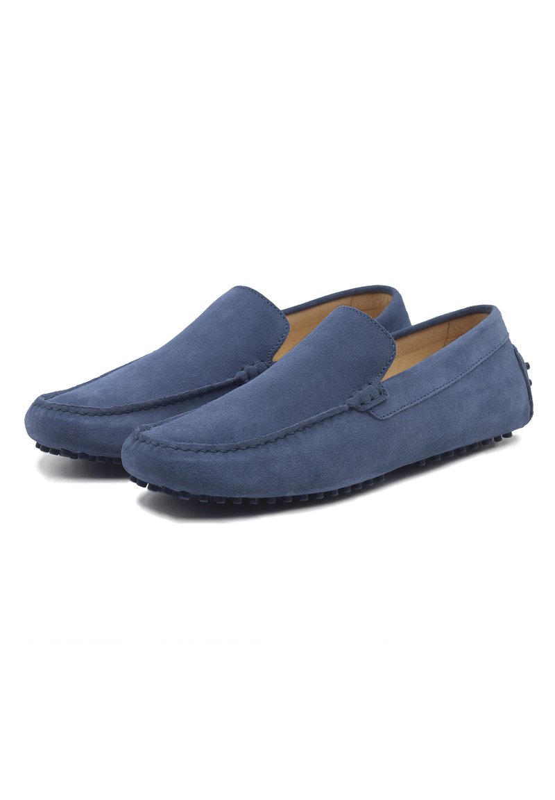 Blauwe suede instappers met een soepele textuur, ronde neus en contrasterende stiksels. De zool heeft kleine rubberen nopjes voor grip.