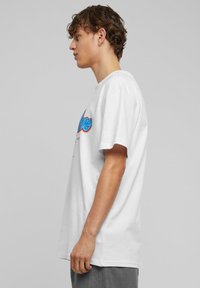 Hvid bomulds T-shirt med korte ærmer, prydet med farverig grafisk tekst på fronten, lige pasform og en blød tekstur.