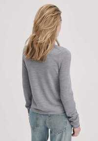 Lichtgrijze longsleeve trui met een gladde textuur, ronde halslijn, aansluitende mouwen en een iets verkorte zoom, gecombineerd met blauwe denim jeans.