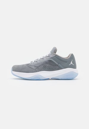 Gray athletic shoe with suede and mesh upper, white laces, and light blue rubber sole. Features a perforated pattern and logo on the heel.