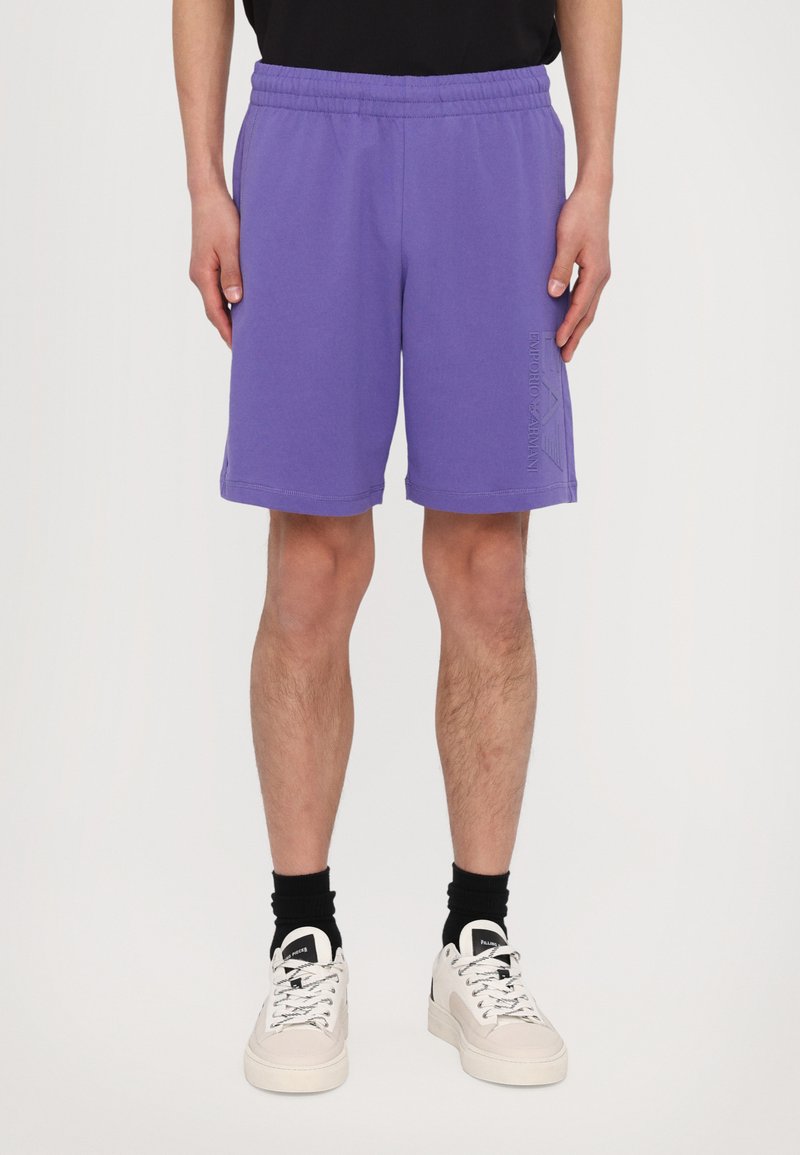 Pantalones cortos de algodón morado con cintura elástica, corte ajustado y bolsillos laterales. Presenta una marca en la pierna derecha.