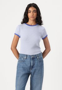 T-shirt listrada em azul claro e branco, com gola e mangas em ribana azul, combinada com jeans azul claro. Mistura de algodão, design ajustado.