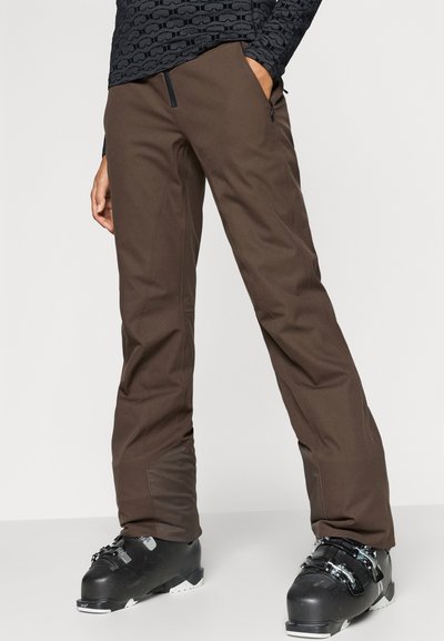 Pruunid suusapüksid, millel on sile tekstuur, istuva lõikega, küljetaskuga luku ja tugevdatud alumiste äärtega vastupidavuse tagamiseks.