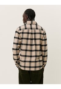 Beige og svart rutete flanellskjorte med knapp-ned krage, bakre yoke, lange ermer og detaljert sidesøm. Myk tekstur.