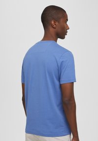 T-shirt da uomo blu a maniche corte in misto cotone, presenta un collo rotondo e un piccolo dettaglio a loop sul retro. Vestibilità aderente con una trama liscia.