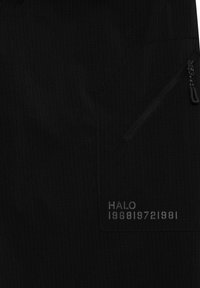 Schwarzer Stoff mit diagonaler Reißverschlusstasche und grauem Text „HALO 196819721981“ unter der Tasche gedruckt.