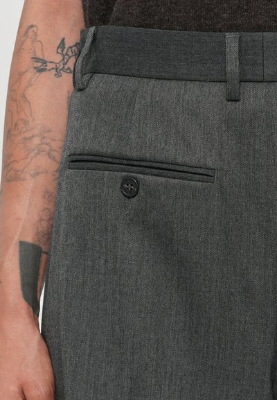 Gray tailored pants feature a smooth texture, a back pocket with a button, and a subtle diagonal weave pattern.