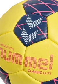 Gul träningsboll med blå yta och rosa detaljer, texturerade mönster och "numel CLASSIC ELITE"-logotyp i rosa.