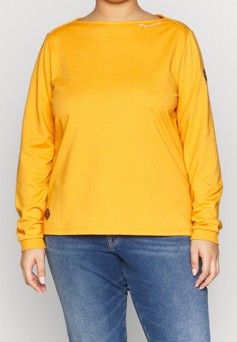Camicia gialla a maniche lunghe realizzata in tessuto morbido con scollatura a barca e maniche lunghe. Presenta un logo sulla parte superiore sinistra e un'etichetta sull'orlo.