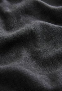 Tissu gris foncé avec une texture douce, légèrement froissée et des fibres tissées visibles sous un éclairage diffus.