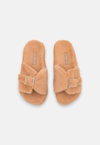 Faux fur slippers in light orange, featuring a bow detail with a silver buckle, open-toe design, and soft, textured surface.