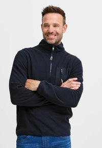 Fleece-Pullover in Marineblau mit hohem Kragen, Frontreißverschluss und einer Brusttasche mit Reißverschluss. Weicher Stoff und lässige Passform.