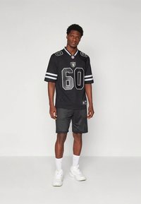 Černý fotbalový dres se šedými akcenty, s číslem 60 a logem týmu. Doplněn černými síťovanými šortkami a bílými teniskami.