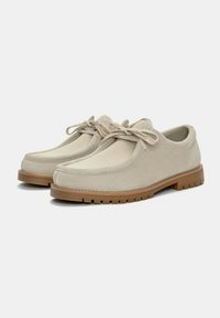 Pantofi din suede bej cu panouri de plasă, vârf rotund și șireturi rotunde. Talpă din cauciuc cu striații texturate pentru aderență. Design casual, potrivit pentru diverse ocazii.